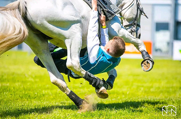 Un voltigeur passe sous le ventre d'un cheval au galop